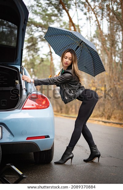 Sexy woman on the heels with broken car on the\
empty road waiting for help.\
