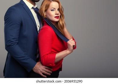 Sexy woman in red holding boss by necktie, seduction