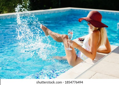 sexy woman relax in swimming pool outdoors. Beautiful female model in swimsuit drink champagne and eat fruits. Summer vacation time in luxury resort.