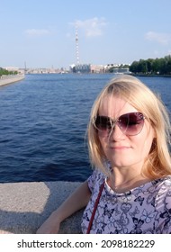 Sexy woman takes a selfie. Wearing dark glasses, with blond hair. Against the background of the river. Summer.