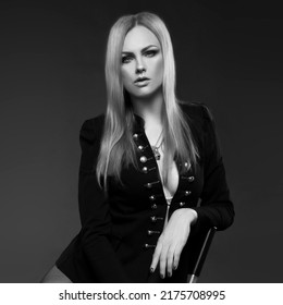 Sexy Woman Wearing Suit Jacket Posing In Studio Dark Background Sitting On Chair. Monochrome