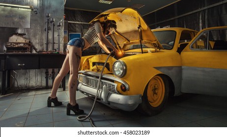 Sexy woman is welding something inside an old car.