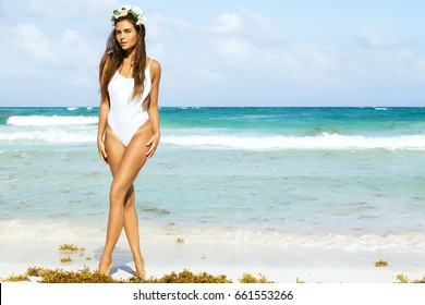 Sexy woman in white swimsuit is posing on the beach