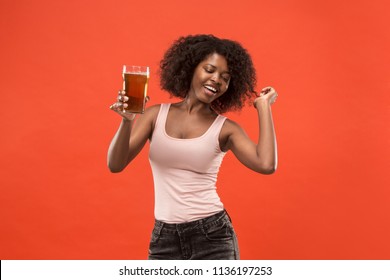 Sexy young african american woman drinking beer over orange studio background