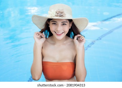 Sexy young asian woman in swimsuits in summer. beautiful woman in orange bikini and hat in swimming pool with tropical drink.