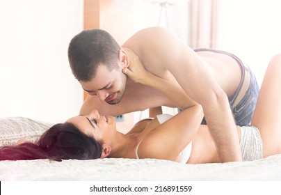 Sexy young couple lying and having foreplay on bed
