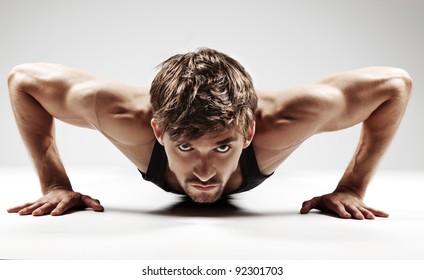 Sexy Young Fashion Sport Man, Fitness Muscle Model Guy Making Push Ups Exercise Over Gray Background.