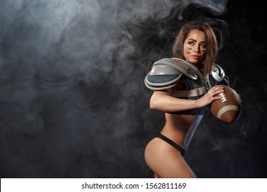 Sexy Young Quarterback Girl With Ball In Smoke. American Football