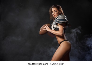 Sexy Young Quarterback Girl With Ball In Smoke. American Football