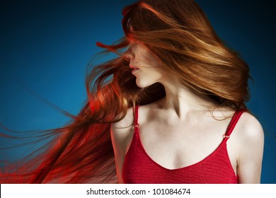 Sexy Young Red Hair Woman In Red Dress On Dark Blue Background