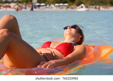 A sexy young woman in bikini on a mattress lilo sunbathing in the sea water at the holiday beach.