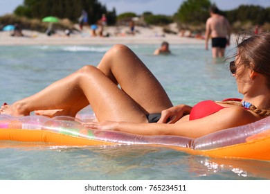 A sexy young woman in bikini on a mattress lilo sunbathing in the sea water at the holiday beach.