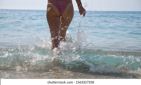 Sexy Young Woman Going Into Sea For Refreshing Or Swimming. Attractive Girl In Pink Bikini Relaxing On Exotic Resort And Enjoying Summertime. Concept Of Travel Or Summer Vacation. Slow Mo Back View