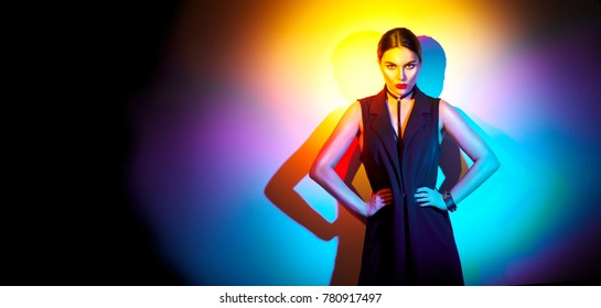 Sexy Young Woman Portrait, On Colorful Background. Seductive Brunette Model Girl Posing In Studio In Black Sexy Clothes, Fashion Accessories, Bright Makeup In Neon Light. Clubber, Night Life Concept