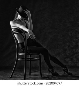 Sexy young woman sitting on a chair on a black background.