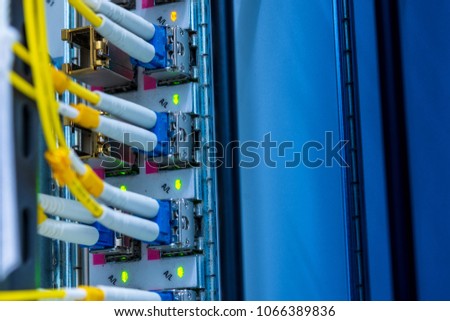 SFP transceiver modules on networking switch in data center room with fiber optics cables connected