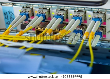 SFP transceiver modules on networking switch in data center room with fiber optics cables connected