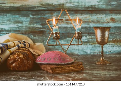 Shabbat eve table with covered challah bread, candles and cup of wine.