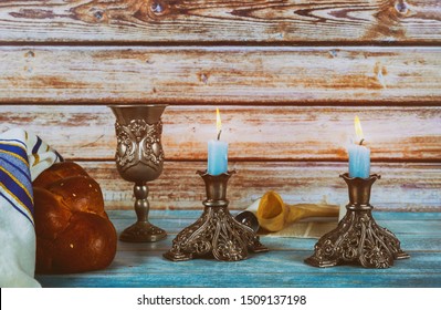 Shabbat Jewish holiday with challah bread on a candles and cup of wine.