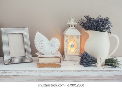 Shabby Chic Interior Decor For Farmhouse. Lavender In Pitcher, Books And Lantern On A Vintage Shelf Over Pastel Wall. Provence Home Decoration.