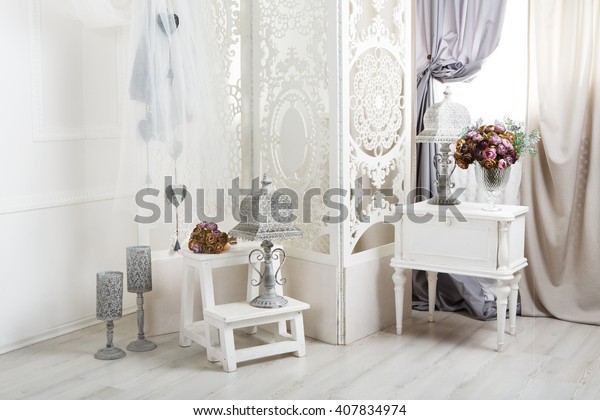 Shabby chic interior.\
Wedding decor, room decorated for rustic wedding, with bedside\
table, folding screen or room divider with white tracery and rose\
bouquets. High key