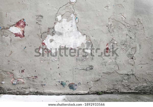 Shabby grey cracked plaster wall with scuffs scratches and old paint stains