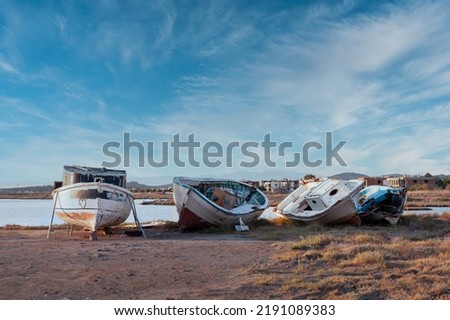 shabby scrap fishing boat. old fishing boats run aground. scrapped small ships under blue sky and clouds