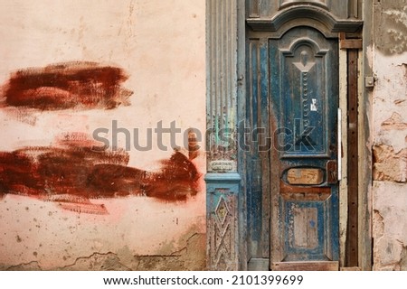 Shabby wooden door in an old building with cracked walls