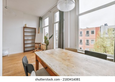 Shabby Wooden Table With Chairs And Vase Located Near Comfortable Couch Against Light Walls With Decorations In Modern Apartment