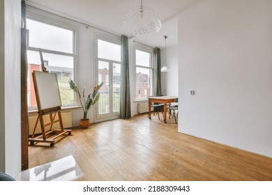 Shabby Wooden Table With Chairs And Vase Located Near Comfortable Couch Against Light Walls With Decorations And TV In Modern Apartment