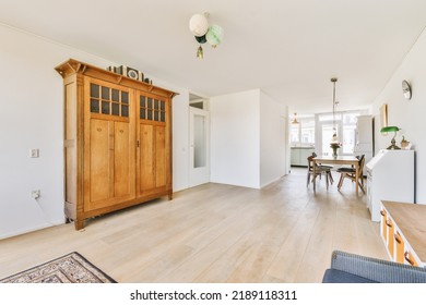 Shabby Wooden Table With Chairs And Vase Located Near Comfortable Couch Against Light Walls With Decorations And TV In Modern Apartment