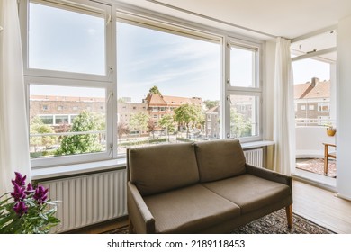 Shabby Wooden Table With Chairs And Vase Located Near Comfortable Couch Against Light Walls With Decorations And TV In Modern Apartment