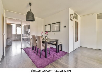 Shabby Wooden Table With Chairs And Vase Located Near Comfortable Couch Against Light Walls With Decorations And TV In Modern Apartment