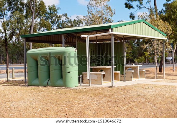 A shade rest stop area with\
seating and tank water for drivers to rest along their\
journey