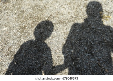 Shade and shadow of Mother and child holding hands and walking on countryside road
