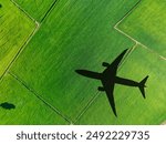 Shadow airplane flying above green field. Sustainable fuel. Biofuel in aviation. Sustainable transportation and eco-friendly flight with biofuel use. Aviation sustainability. Biofuel in air travel.