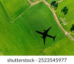 Shadow airplane flying above green field. Sustainable aviation fuel. Sustainable transportation and eco-friendly flight with biofuel use. Aviation sustainability. Air travel. Reduce carbon footprint.