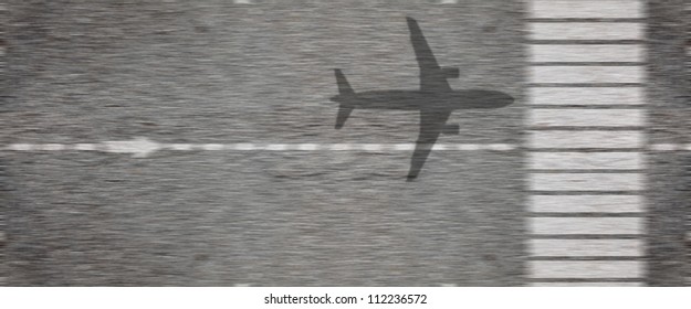 Shadow of an airplane taking off from an airport runway tarmac at high speed.