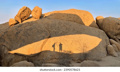 Shadow of the Arch at Spitzkoppe with the shadows of two people standing underneath the arch. At sunrise dawn