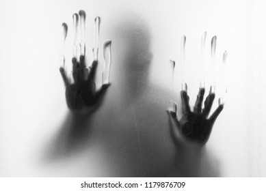 Shadow blur of horror man.Hands on the glass.Dangerous man behind the frosted glass.Mystery man.Halloween background.Black and white picture.Blur picture - Powered by Shutterstock