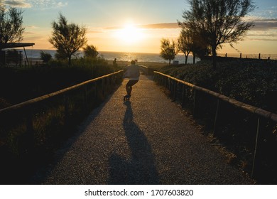 
shadow of a boy skating towards the sunset on a beach - Powered by Shutterstock