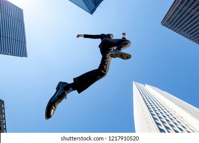 A  shadow of businessman jumping with the blue sky and skyscrapers background . Energetic · Power · Success · Challenge Image - Powered by Shutterstock