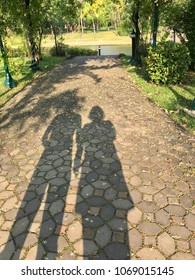 Shadow of couples holding hands on brick tiled road in the park, shadow of man and woman walking together in the park