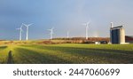 Shadow of a cyclist in the evening light on a meadow - in the background wind turbines and a grain silo on a farm, Romrod, Central Hesse, Germany