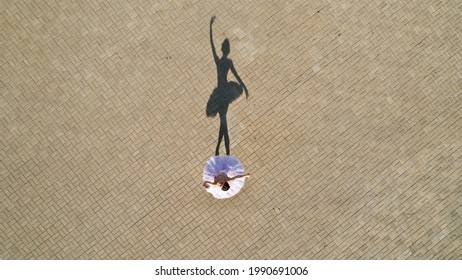 The shadow of a dancing ballerina in tutus. Photo from above on the street in sunny weather. Classical dance.