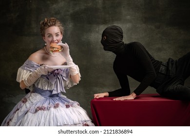 Shadow of diet. Cinematic portrait of young beautiful woman in image of medieval royal person in renaissance style dress and her servant, page isolated on dark vintage background. Comparison of eras