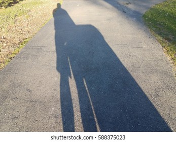 Shadow In Driveway Of Man Taking Out The Garbage Can