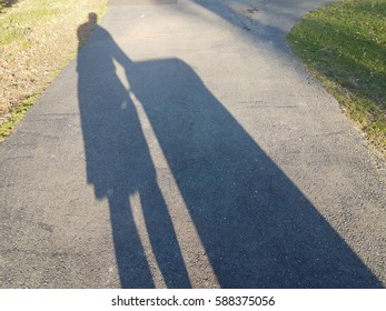 Shadow In Driveway Of Man Taking Out The Garbage Can