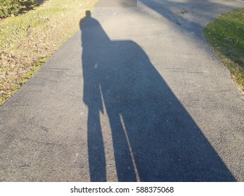 Shadow In Driveway Of Man Taking Out The Garbage Can