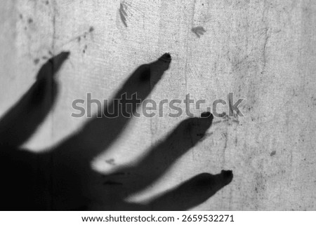 Shadow of eerie hands with long nails behind a curtain against light, creating a spooky ghost-like scene perfect for horror, thriller, and supernatural themes.